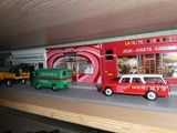 des petites voitures et des camions sont posés sur une étagère devant un magasin