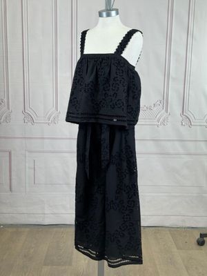 a black dress on a mannequin stand in front of a white wall