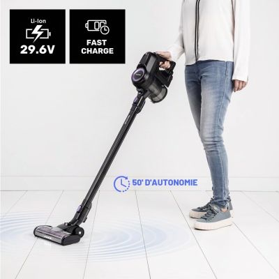La femme utilise un aspirateur sans fil pour nettoyer le sol.