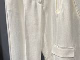 un pantalon de survêtement blanc suspendu à un cintre devant un mur noir