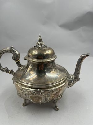 une théière en argent avec un couvercle, posée sur un socle