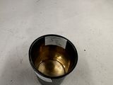 une tasse en métal posée sur une surface blanche