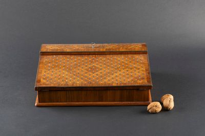an old wooden box with two walnuts next to it on a gray surface