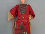 une vieille poupée vêtue d'une robe rouge et coiffée d'une couronne dorée