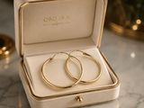 a pair of gold hoop earrings sitting in a box