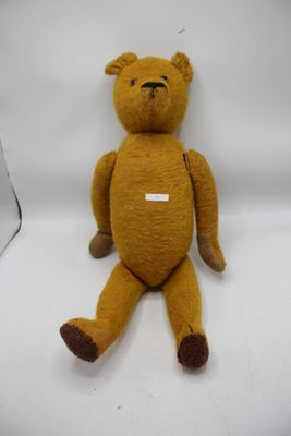 un ours en peluche marron assis sur une surface blanche