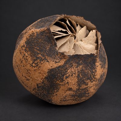 un vase marron contenant une feuille, sur fond noir