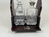 two glass decanters on a wooden stand on a white surface