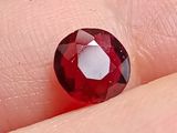 un gros plan sur le doigt d'une personne, sur lequel est monté un diamant rouge
