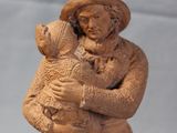 wooden statue of a man holding a baby and a dog
