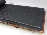 a black leather chaise with a roll of fabric on top of it