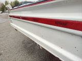 a white boat with a red stripe parked in a parking lot