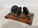 paire de verres anciens plaqués laiton, posés sur un socle en bois, sur un support blanc