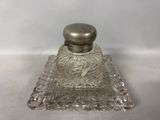 an image of a glass perfume bottle with a metal lid
