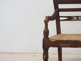 a wooden chair with a wicker seat on a white floor