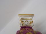 a purple vase with a gold decoration on the top of it