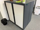 a black and white cabinet in a room with a trash can
