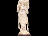 a white statue of a woman holding a flower on a black surface