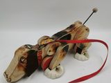 an image of a wooden toy dog with a red leash on a white surface