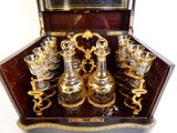des bouteilles et des verres dans un coffret posé sur une table, avec un miroir en arrière-plan