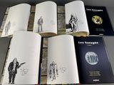 several open books with drawings of people on them sitting on top of a table