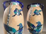 two vases with birds painted on them sitting on a table