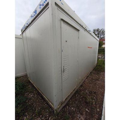 un grand bâtiment blanc avec une porte métallique et un toit bleu