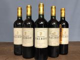 four bottles of red wine are lined up on a table