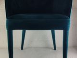 the back of a blue chair with a black seat on a white surface