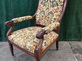 an old chair with a floral upholstered seat and arms