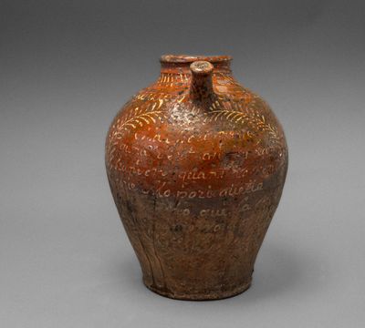 un vieux vase marron portant une inscription, posé sur une surface grise