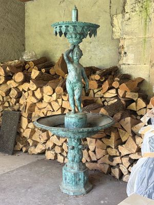 a statue of a boy on a fountain in front of a pile of firewood