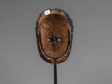 a close up of a wooden mask on a metal stand