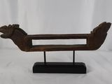 une vieille sculpture en bois représentant un oiseau, posée sur un socle noir