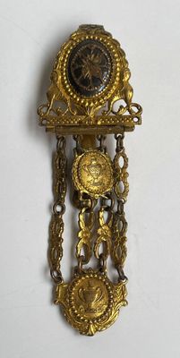 une horloge en or accrochée au mur, entourée d'une chaîne