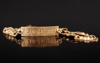 un gros plan d'un bracelet en or orné de perles sur un fond noir