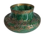 un vase vert orné de motifs dorés sur fond blanc