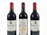trois bouteilles de vin rouge sont alignées sur une surface blanche