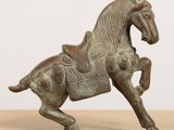 an old bronze statue of a horse on a wooden table