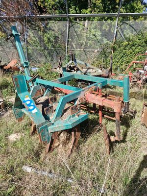 une charrue bleue posée dans l'herbe près d'une clôture