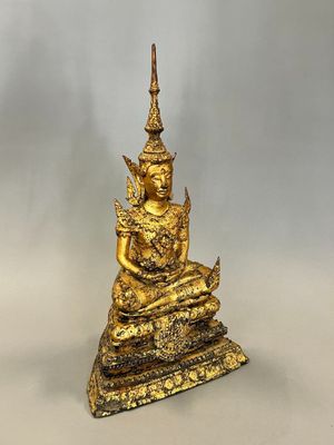 une statue en or représentant une personne assise sur une pile de livres