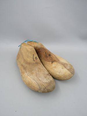 une paire de sabots en bois posés sur une surface blanche, avec un cordon bleu