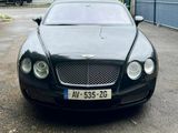 black bentley car parked in a parking lot next to a fence