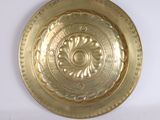 une assiette en or ornée d'un motif sur un fond blanc