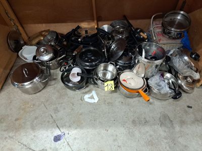 une pile de casseroles et de poêles posée par terre