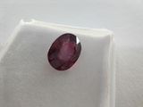 a close up of a red ruby stone on a white surface
