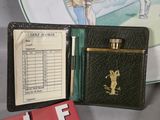 a black leather case with a golf score book and a pen in it