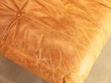 a brown leather ottoman with a button on it