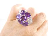 someone is holding a purple and white diamond ring in their hand