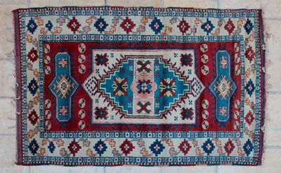 a red and blue rug on a tiled floor next to a brick wall